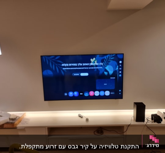טלוויזיה מותקנת על קיר עם מדף תחתון
